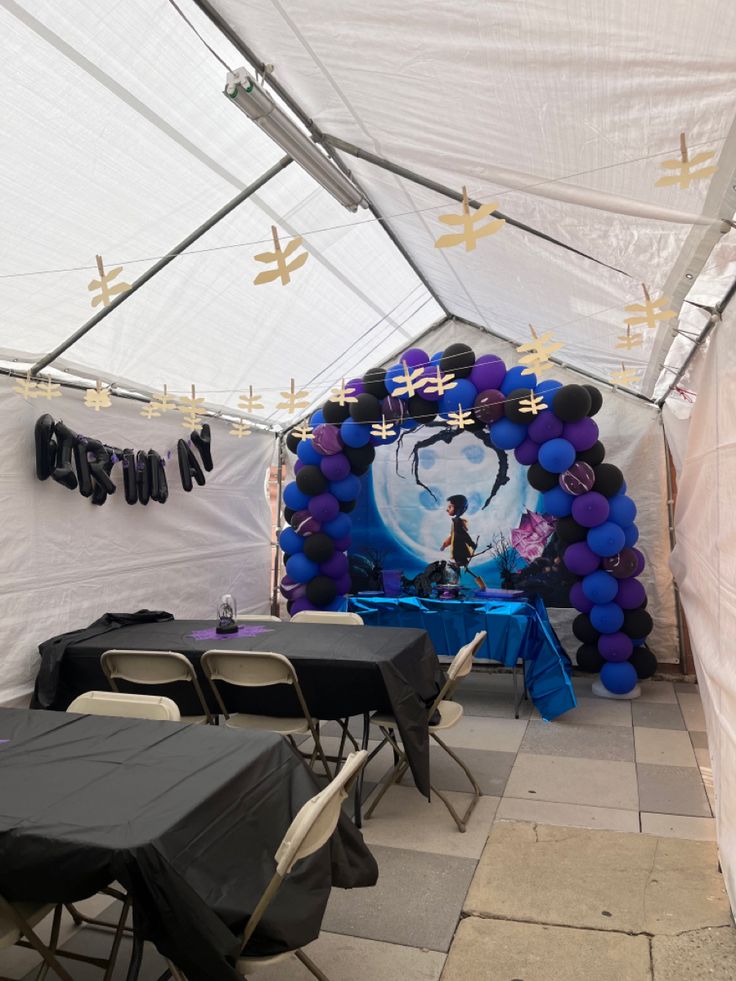 tables and chairs are set up in front of a large balloon arch with an avatar on it