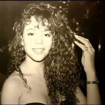 a black and white photo of a woman with long curly hair wearing a strapless top