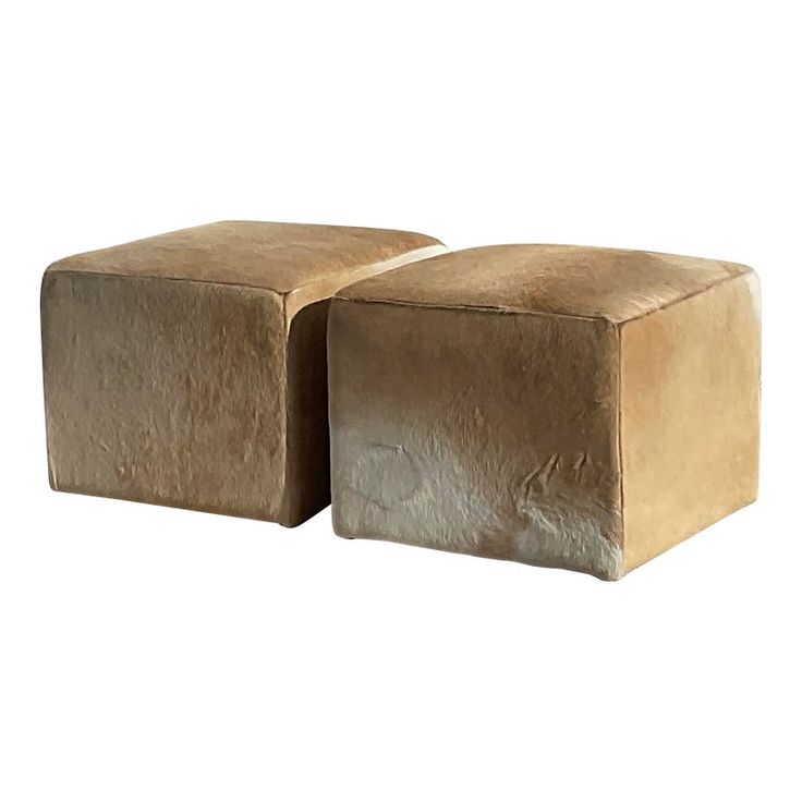 two square stools made out of brown suede material, each with one foot on the ground