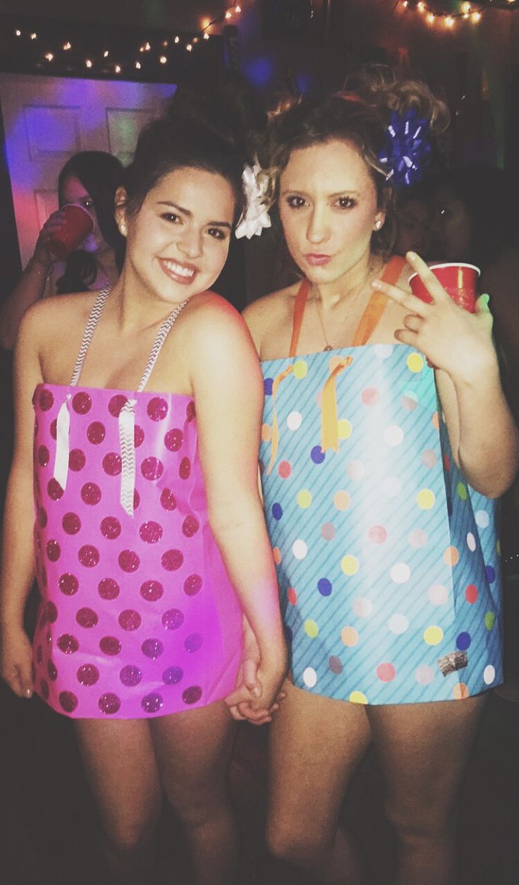 two young women in bathing suits standing next to each other at a party, one holding a drink and the other smiling