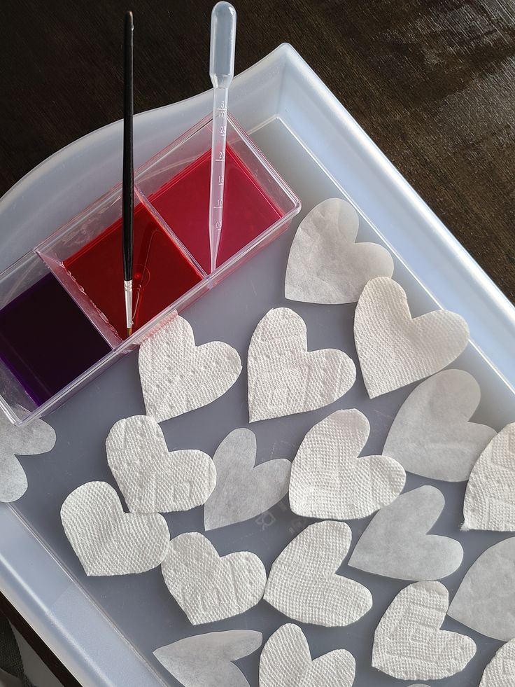 heart shaped paper hearts are sitting on a tray next to a paint container and brush