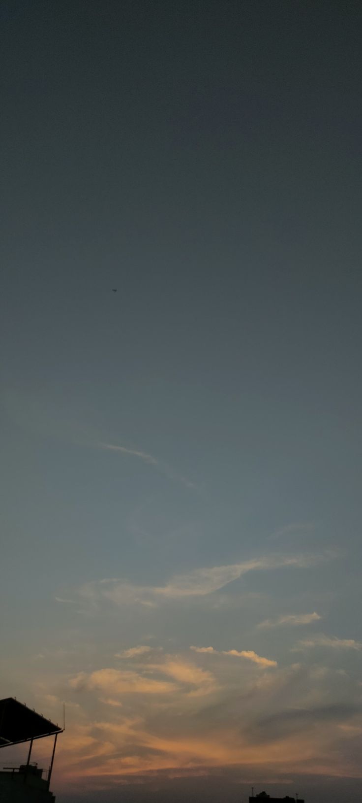 the sun is setting over an ocean with people sitting under umbrellas on the beach