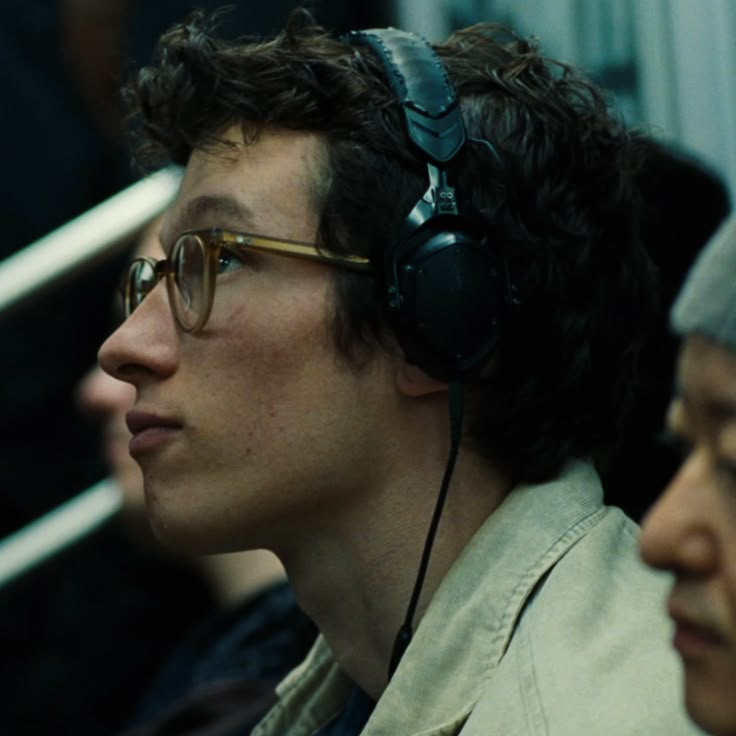 two people sitting next to each other with headphones on their ears and one wearing glasses