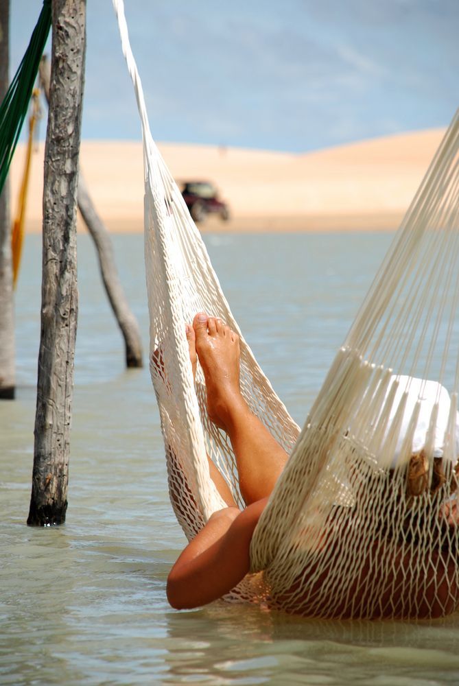 a woman laying in a hammock on the beach