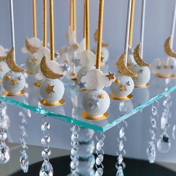 there are some desserts on a glass plate with gold and silver decorations hanging from them