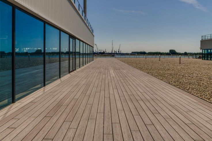 an empty boardwalk next to a building with large windows