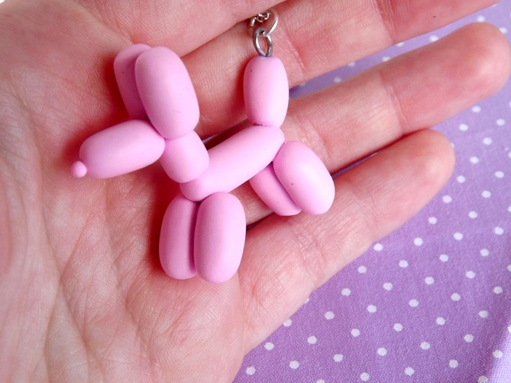 a small pink toy dog sitting on top of someone's hand with a keychain