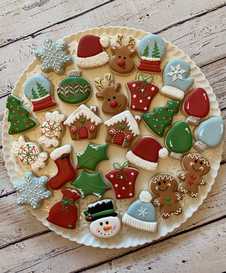 a white plate topped with lots of different decorated cookies and christmas decorations on top of a wooden table