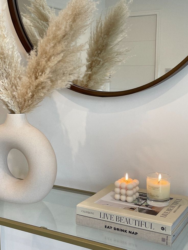 a white vase sitting on top of a table next to a book and candle holder