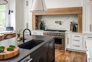 a kitchen with white cabinets, black counter tops and an island in front of the sink