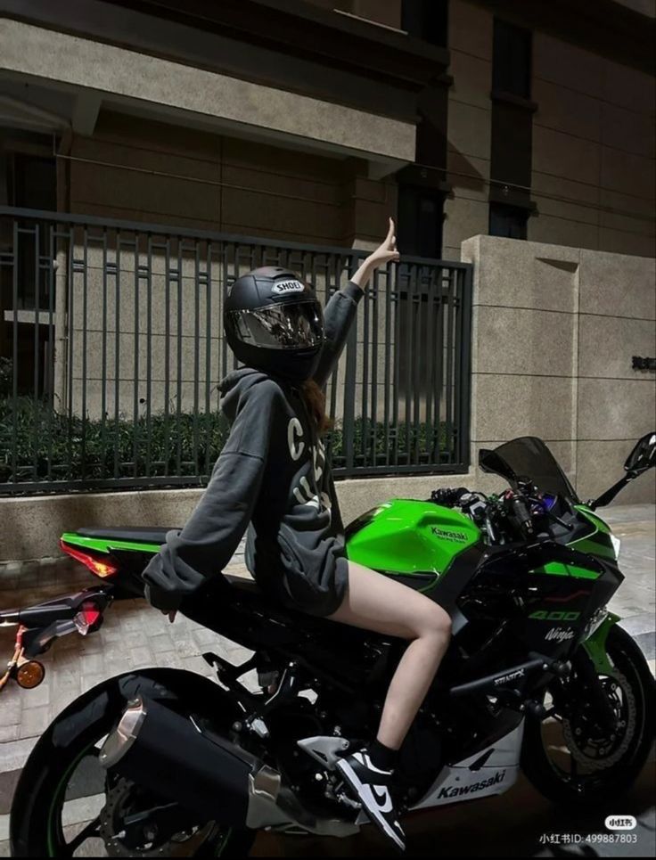 a woman sitting on top of a green motorcycle