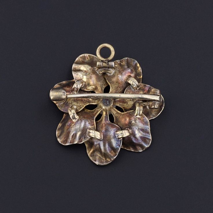 A touch of springtime to brighten any chain or lapel! This antique 14k gold pendant (circa 1900-1910) doubles as a brooch and features a flower adorned in iridescent peach enamel with a pearl accent at its center. The piece measures 1 inch by 1 inch and is in excellent condition. Materials: Pearl, Gold. Antique Gold Flower Jewelry, Elegant Flower Pendant Brooch Jewelry, Elegant Flower Pendant Brooch, Art Nouveau Rose Gold Jewelry As A Gift, Art Nouveau Rose Gold Jewelry As Gift, Art Nouveau Rose Gold Jewelry For Gift, Art Nouveau Rose Gold Jewelry Gift, Rose Gold Art Nouveau Jewelry For Gift, Vintage Gold Brooch With Pearl Pendant