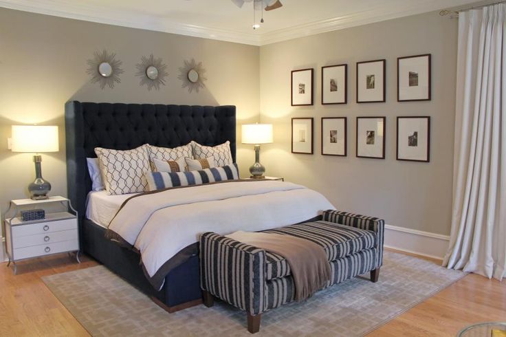 a bedroom with a bed, ottoman and pictures on the wall above it's headboard