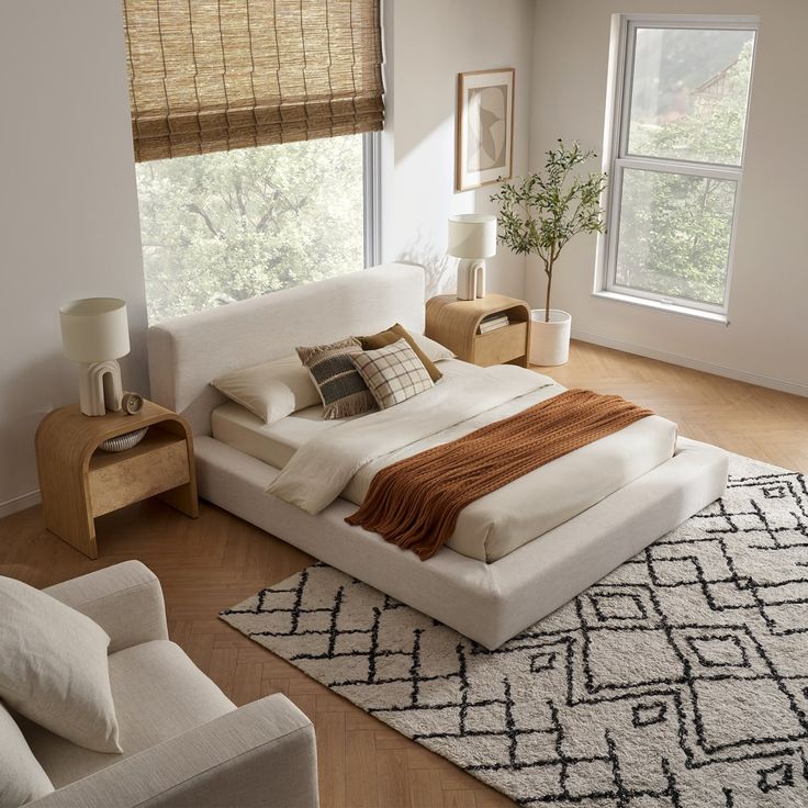 a large bed sitting on top of a wooden floor next to two white couches