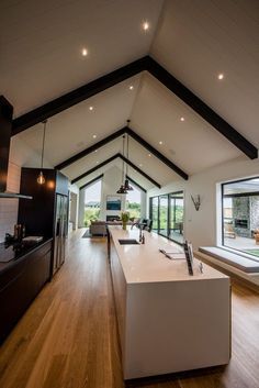 an open kitchen and dining room with wood floors, white walls and ceiling beams is shown