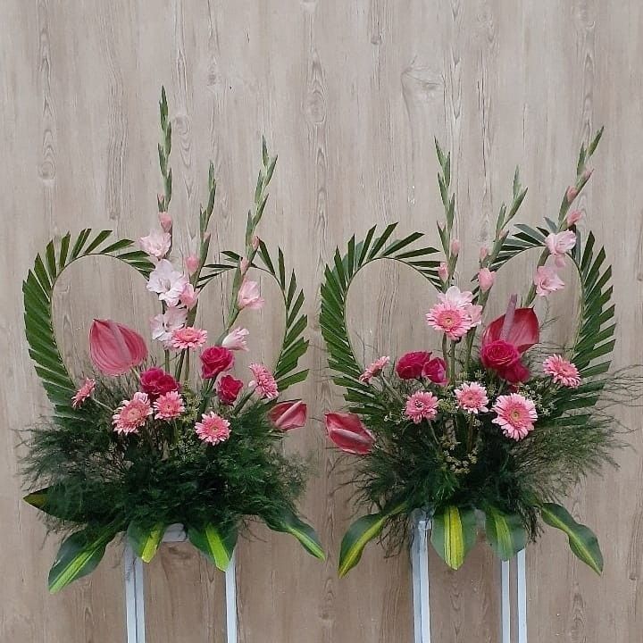 two vases with pink flowers and greenery in them