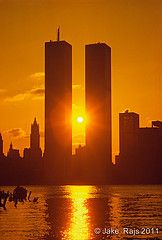 the sun is setting in front of some tall buildings and people are swimming in the water