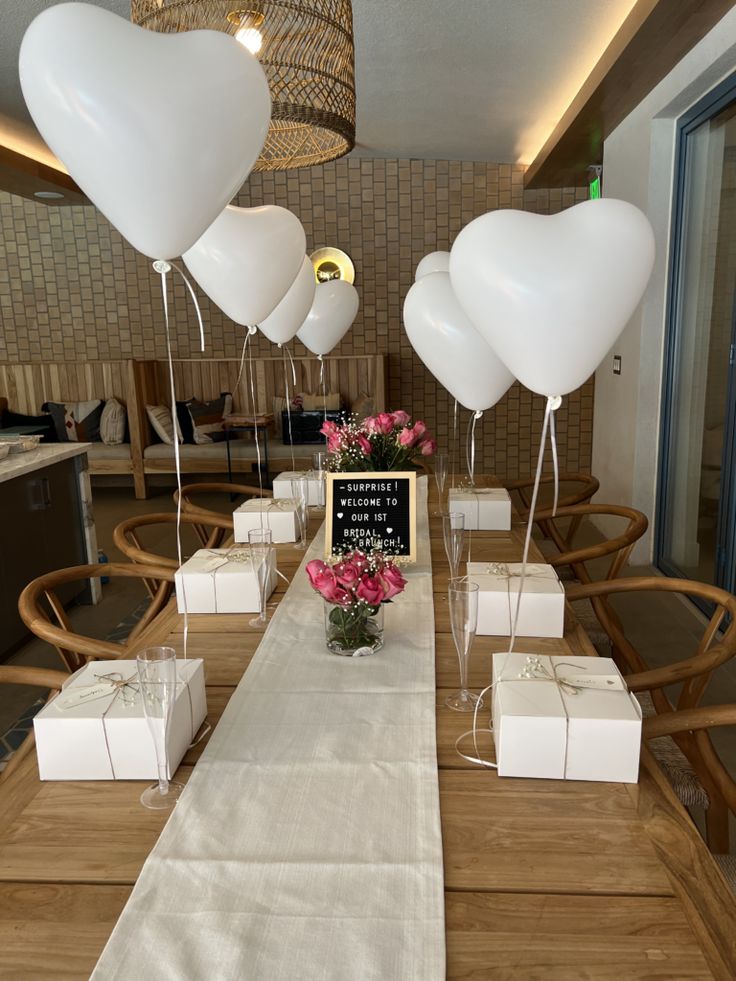 a table set up with white balloons and gift boxes