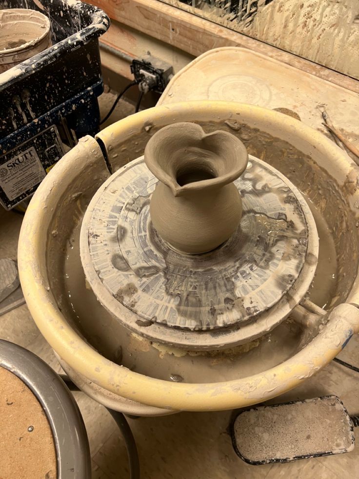 an unfired heart shaped vase made from clay sitting on a potter’s wheel. Potter Aesthetic Clay, Wheel Thrown Pottery Forms, Ceramic Vase Wheel Thrown, Pottery Throwing Aesthetic, Ceramics Class Aesthetic, Pottery Asthetic Ideas, Wheel Projects Pottery, Simple Wheel Thrown Pottery, Ceramics Wheel Ideas