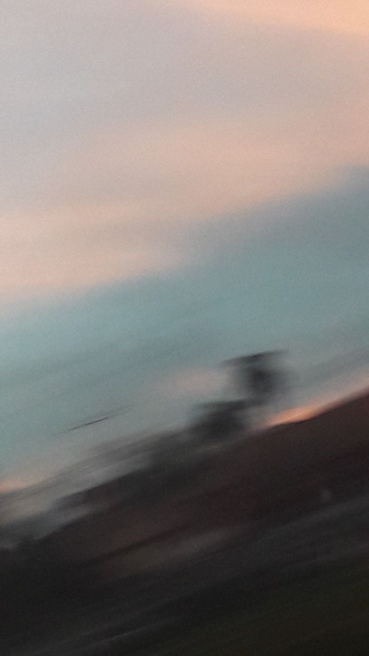 a blurry photo of a person on a snowboard in the air with mountains in the background