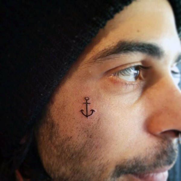 a man with a small anchor tattoo on his forehead