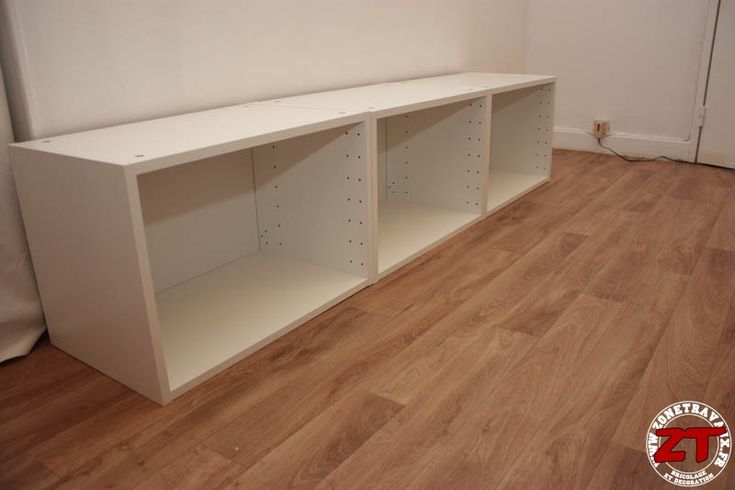 an empty white shelf in the corner of a room with hard wood floors and walls