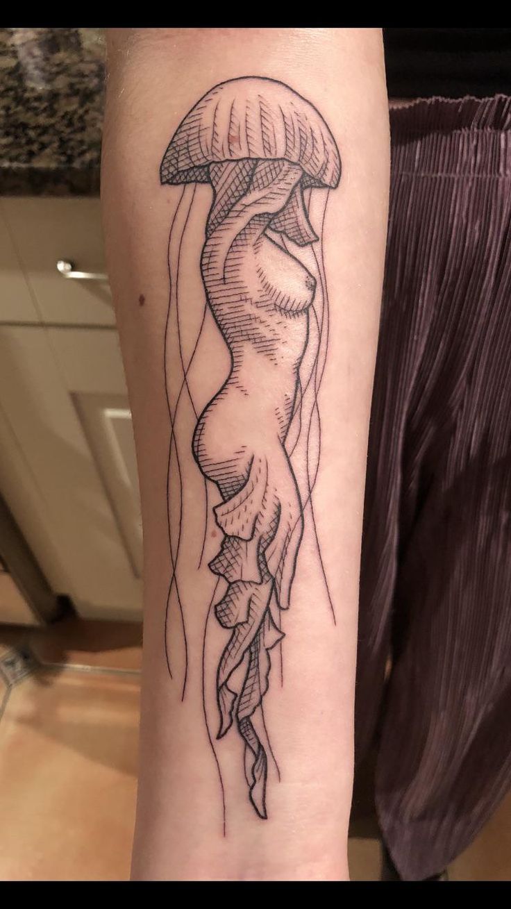 a black and white image of a jellyfish tattoo on the left arm, with an octopus coming out of it's tentacles