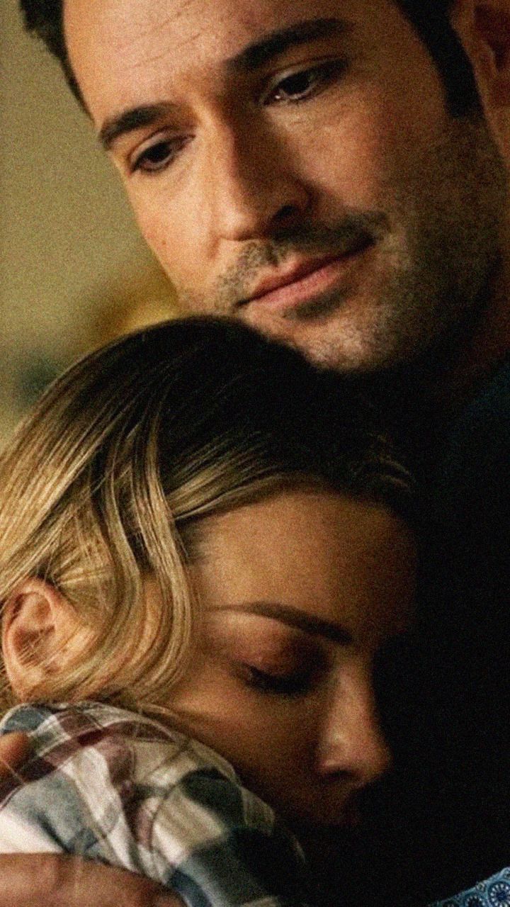 a man and woman embracing each other while looking at something on the screen in front of them