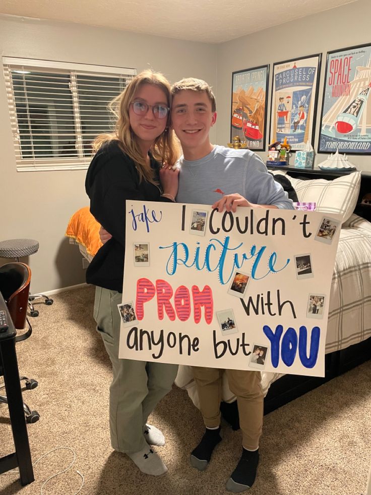 a man and woman standing in front of a bed holding a sign that says i couldn't pride prom with anyone but you