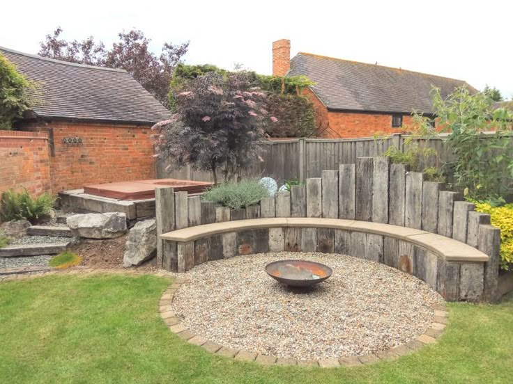 a stone bench sitting in the middle of a yard next to a wooden fence and flowers