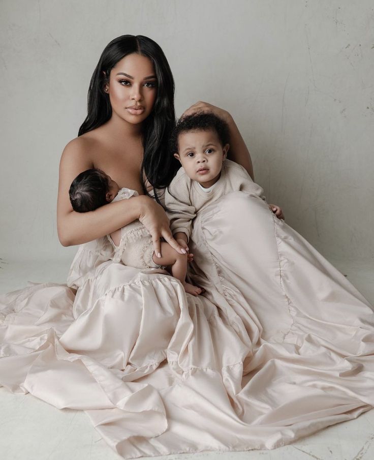 a woman in a white dress holding a baby on her lap and posing for a photo