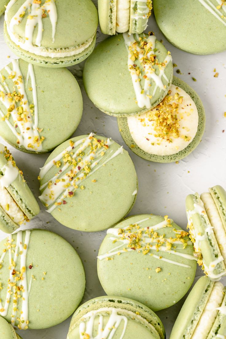 green macaroons with white frosting and sprinkles on them are arranged in rows