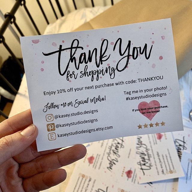 a person holding up a thank you for shopping card