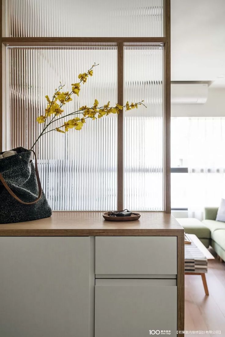 a purse sitting on top of a counter next to a vase filled with yellow flowers