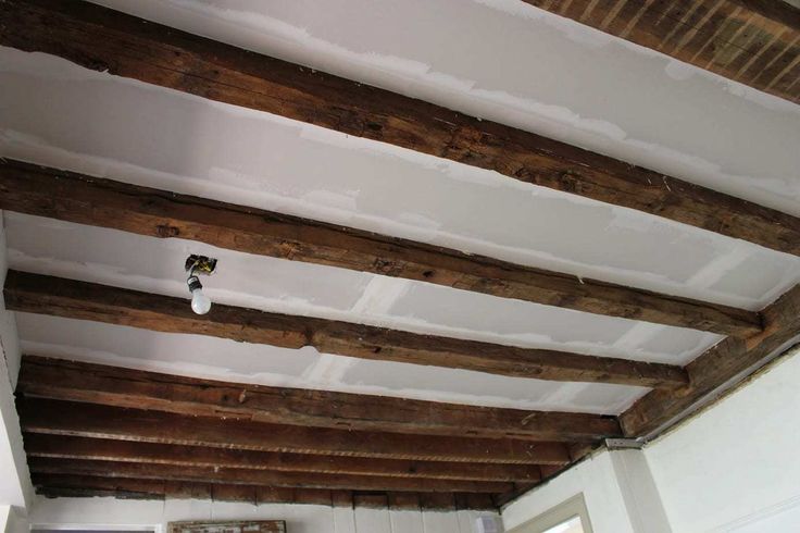 an unfinished ceiling with exposed wood beams and white walls