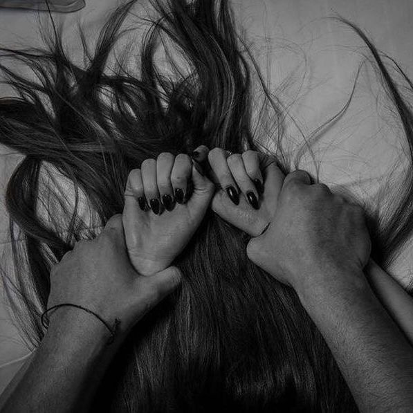 two people holding hands over their head on top of a white sheet with hair flying in the air