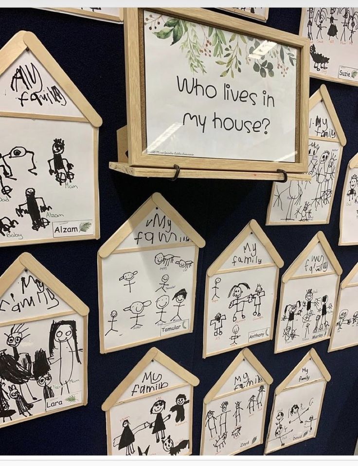 a bunch of drawings are hanging on the wall in front of a sign that says who lives in my house?