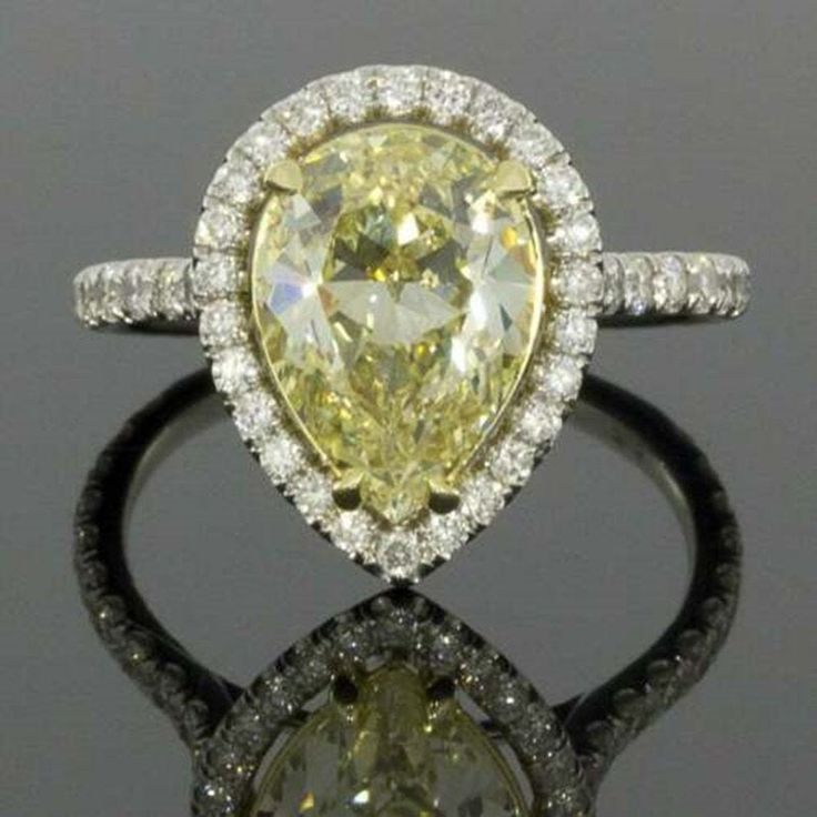 a fancy yellow diamond ring with white diamonds on the band and an oval shaped center stone