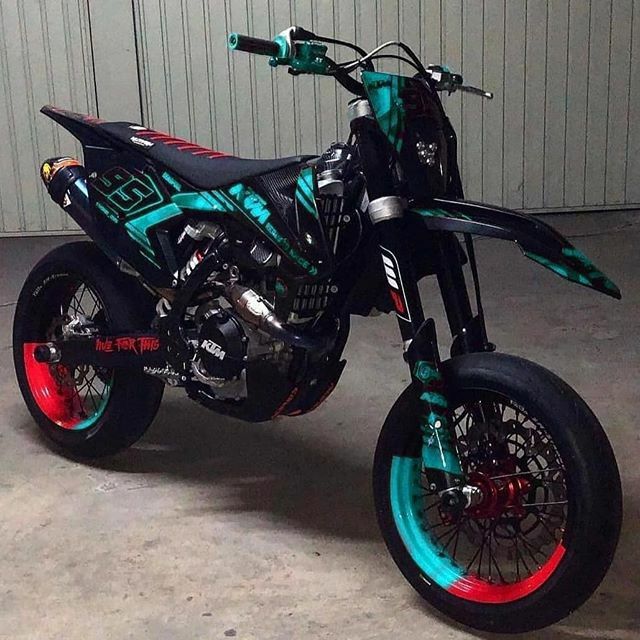 a dirt bike parked in a garage next to a metal building with red and blue rims