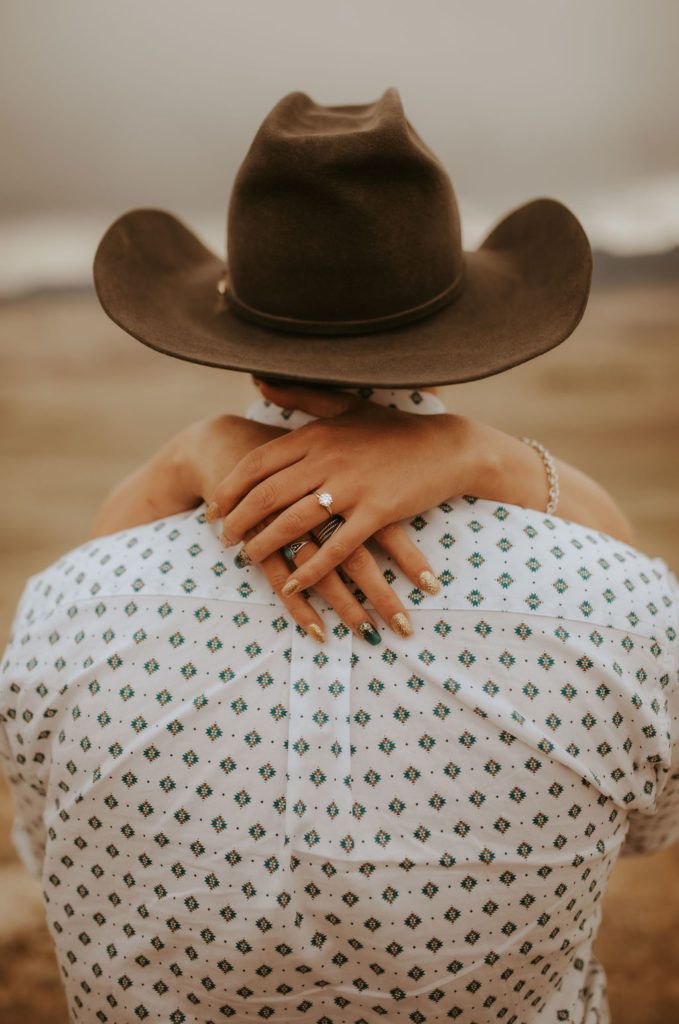 a woman wearing a cowboy hat hugging her back