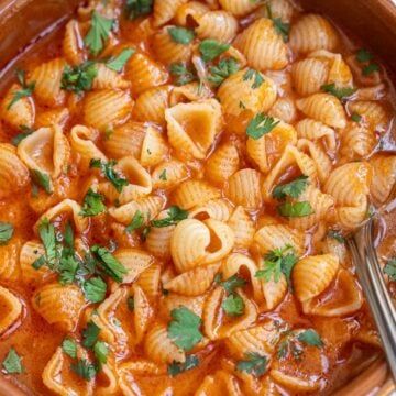 a bowl filled with pasta and garnished with parsley on the side, ready to be eaten