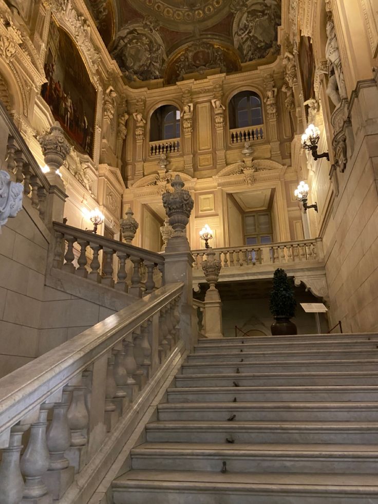 an ornate building with marble stairs and chandeliers on either side of the staircase