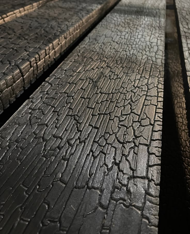 two wooden benches sitting next to each other on top of a cement floor covered in cracks