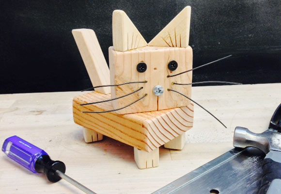 a wooden cat sitting on top of a table next to a pair of scissors