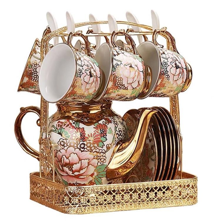 an ornately decorated tea set with matching cups and saucers on a gold tray