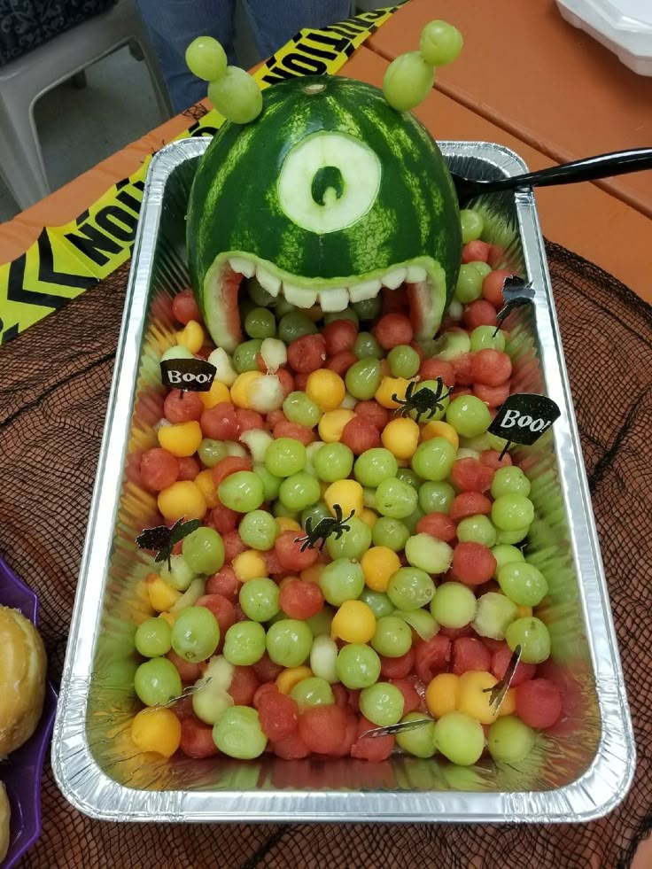 a watermelon shaped like a monster with its mouth full of grapes and other fruits