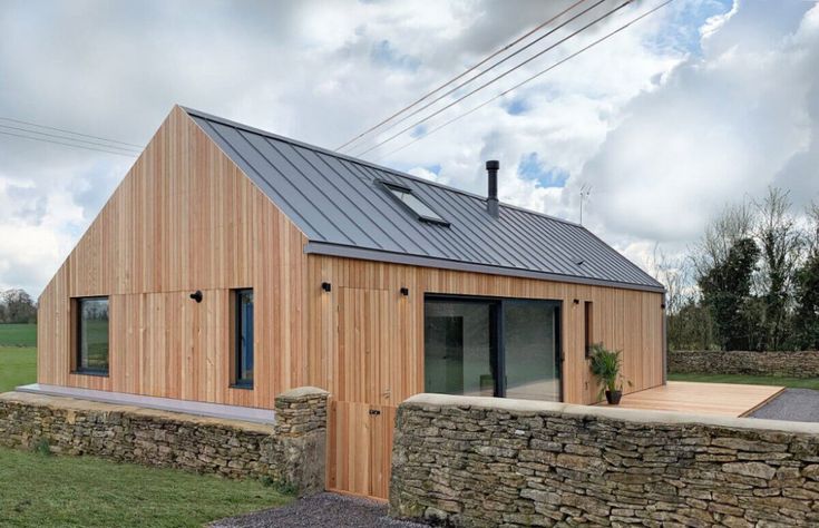 a small wooden house sitting on top of a lush green field next to a stone wall