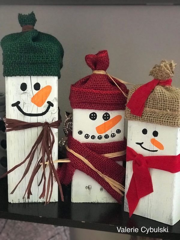 three snowmen made out of wood sitting on top of a table