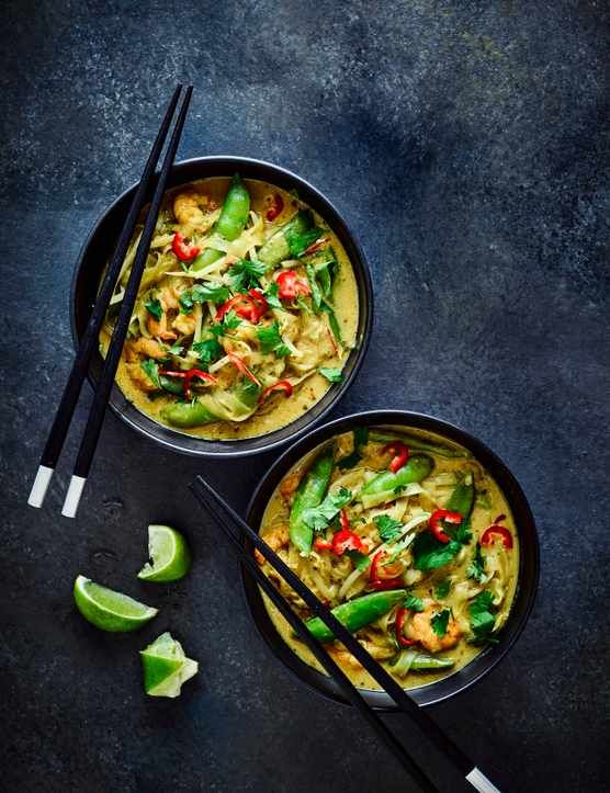 two bowls filled with food next to chopsticks on top of a black table