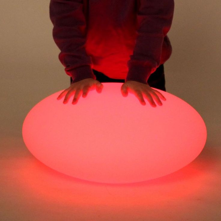 a person standing next to a large round light up object with their hands on it